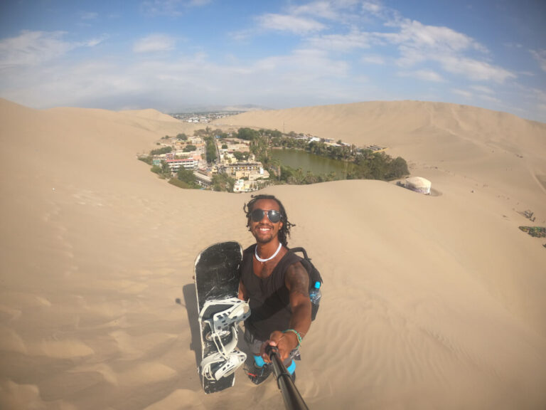 Man sandboarding in Huacachina, a place that's part of a 3-week peru itinerary